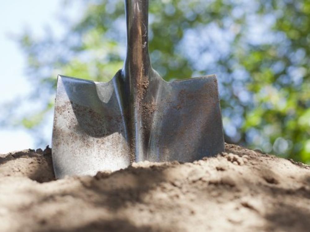 Close-up of a shovel blade pressed into soil while digging.